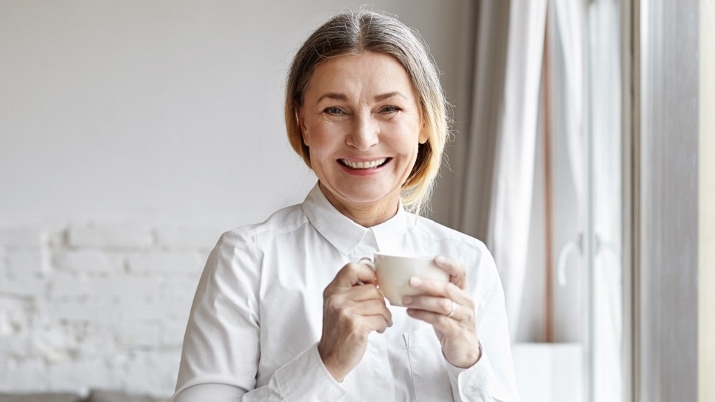 Smiling woman in a living room holding a cup