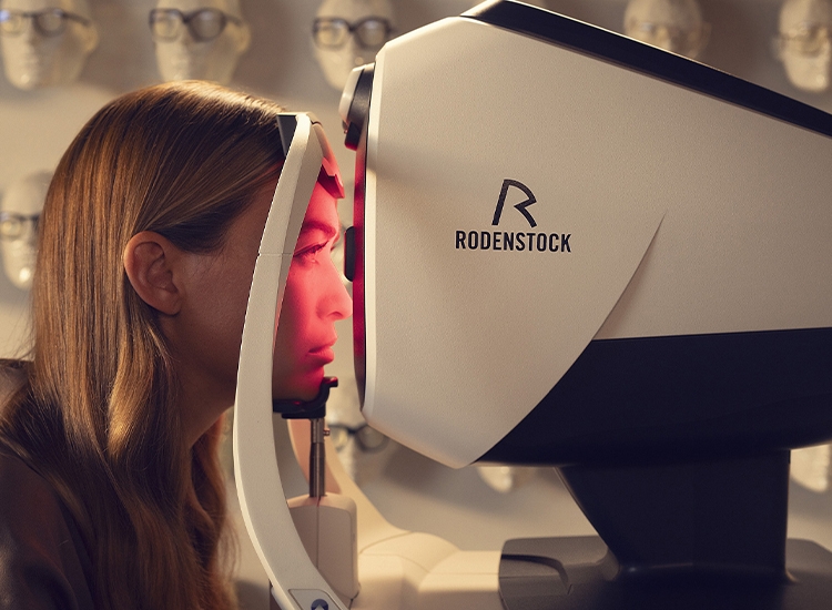 Woman sitting in front of the DNEye scanner during an eye examination