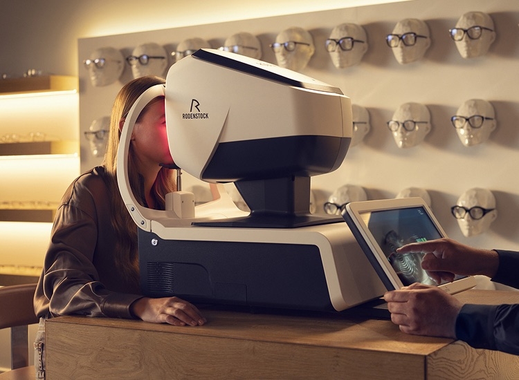 An optician measures a customer's eyes with the DNEye scanner